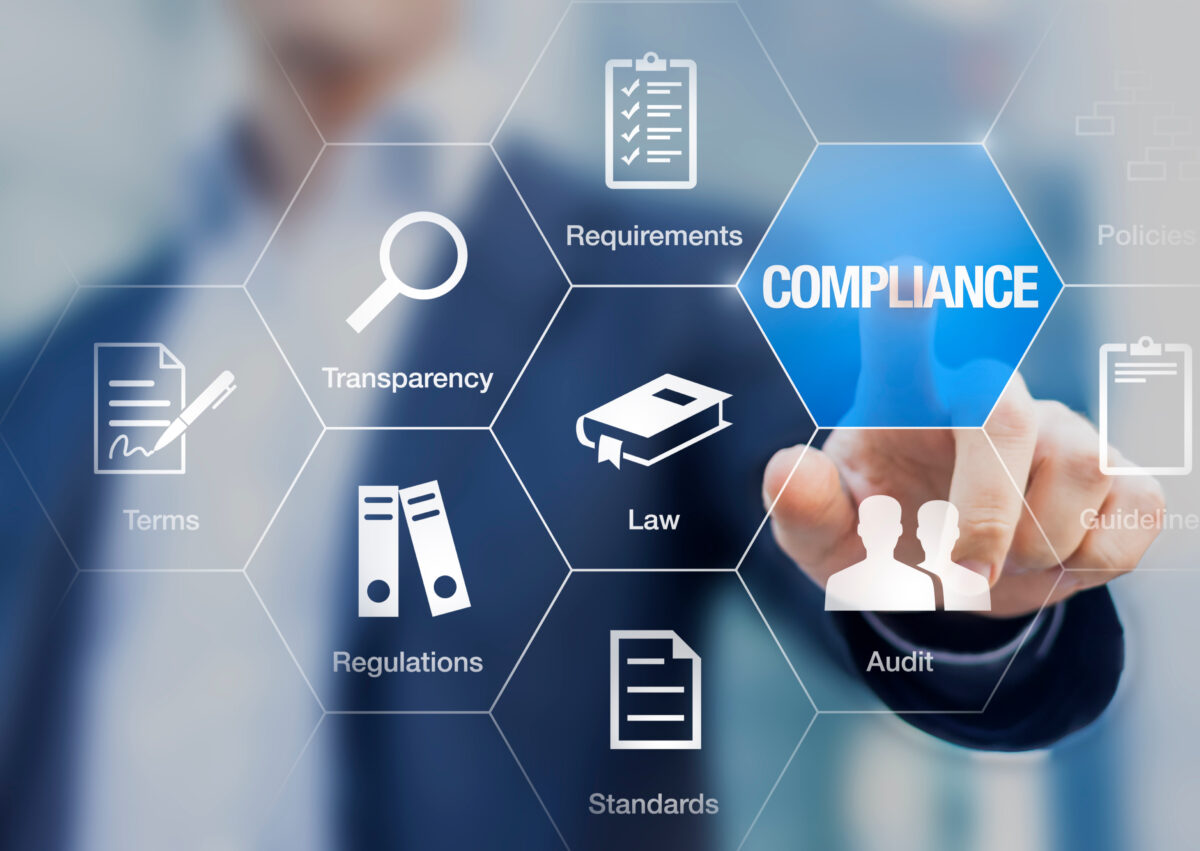 A person in business attire touches a hexagonal digital interface with the word “COMPLIANCE” highlighted. Surrounding icons and labels include requirements, transparency, terms, regulations, standards, law, audit, and guidelines.