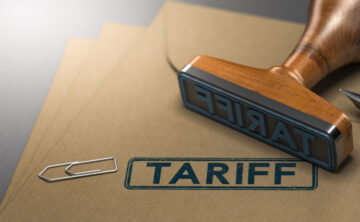 Rubber stamp imprinting the word “Tariff” on a stack of manila documents.