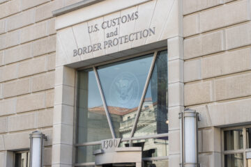 Entrance to a building labeled "U.S. CUSTOMS and BORDER PROTECTION" with address "1300" above the door.
